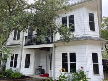 Charming white two-story home with balcony, black trim, and manicured landscaping at 514 Blockade Dr., Pawleys Island, SC 29585