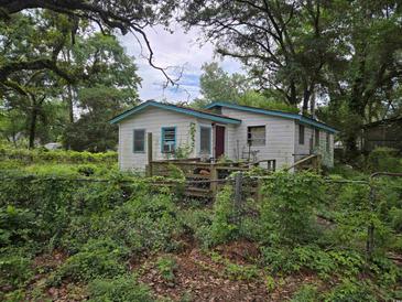 Exterior shot of a weathered home with a wooden porch and an overgrown front yard at 564 Baker Ave., Murrells Inlet, SC 29576