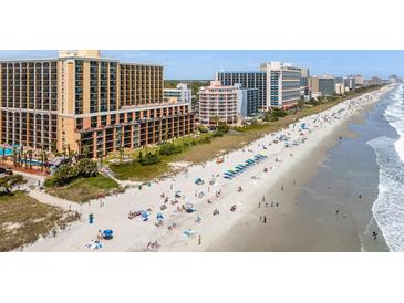 Wide, sandy beach with oceanfront hotels and umbrellas, showcasing a vibrant coastal scene at 6900 N Ocean Blvd. # 421, Myrtle Beach, SC 29572