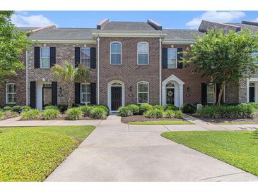 Charming brick townhomes featuring manicured lawns, shuttered windows, and private front entries at 750 Howard Ave. # E, Myrtle Beach, SC 29577