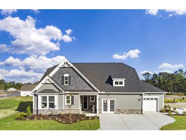 Charming two-story home featuring gray siding, stone accents, and a well-manicured front lawn under a bright blue sky at 866 Fowler Rd., Conway, SC 29526