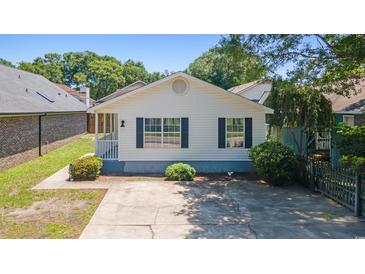 Charming home featuring a concrete driveway, small porch and black shutters in a neighborhood full of trees at 10071 Kings Rd., Myrtle Beach, SC 29572