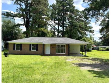 Charming brick home with a well-manicured front yard, mature trees, and a covered carport at 109 S Maple Ave., Andrews, SC 29510