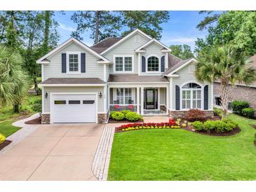 Charming two-story home with a well-manicured lawn, beautiful landscaping, and a welcoming front porch at 124 Turtle Creek Dr., Pawleys Island, SC 29585