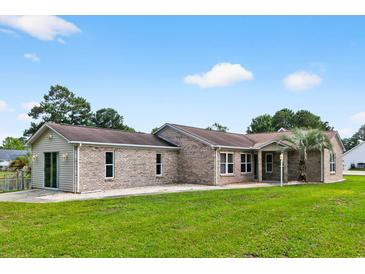 Charming single-story brick home featuring a lush green lawn and mature trees at 131 Pine Lake Circle, Ocean Isle Beach, NC 28469