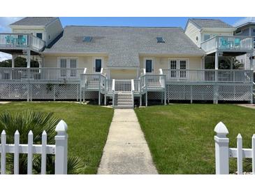 Charming beach house featuring symmetrical design, white picket fence, and well-maintained lawn at 4806 S Ocean Blvd., Surfside Beach, SC 29575