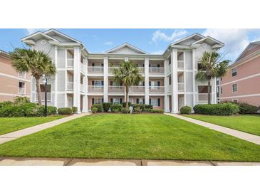 Inviting multi-story condo building featuring manicured lawn, palm trees, and private balconies at 627 Waterway Village Blvd. # 8E, Myrtle Beach, SC 29579