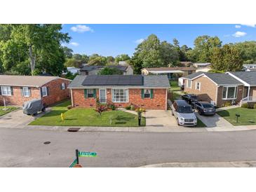 Charming brick home with manicured lawn and solar panels on roof at 1145 Forest Dr., North Myrtle Beach, SC 29582