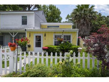 Charming yellow home featuring a white picket fence, lush garden, and vibrant flowers, creating a welcoming curb appeal at 12 Century St. # 12, Myrtle Beach, SC 29577