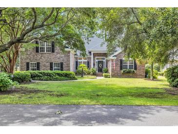 Charming brick home with lush green lawn, mature trees, and inviting front entrance at 139 Olde Canal Loop, Pawleys Island, SC 29585