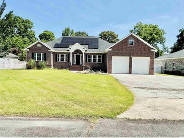 Charming brick home with a well-manicured lawn, solar panels, and attached two-car garage at 1421 Shoreline Dr., Myrtle Beach, SC 29577
