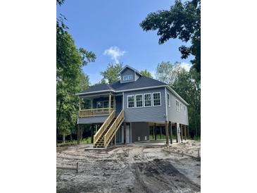 Exterior of a two-story coastal home with gray siding, wood stairs, and a porch overlooking the sandy yard at 2075 Lees Landing Circle, Conway, SC 29526