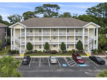 Three-story condo building with white railings, stairs, parking, and landscaping at 4261 Hibiscus Dr. # 4-104, Little River, SC 29566