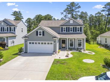 Charming two-story home featuring gray siding, a two-car garage, and a well-manicured front yard with green grass at 597 Heritage Downs Dr., Conway, SC 29526
