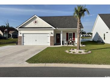 Charming home with a two-car garage, beautifully landscaped yard and inviting front porch seating at 668 Rycola Circle, Surfside Beach, SC 29575