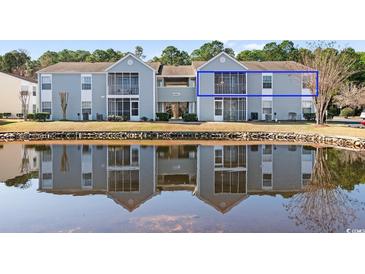 Condo exterior reflecting in the pond, highlighting a serene setting with lush landscaping at 8861 Chandler Dr. # F, Surfside Beach, SC 29575