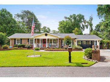 Charming brick home featuring a welcoming front porch and a well-manicured lawn with mature trees at 280 Morgan Ave., Little River, SC 29566
