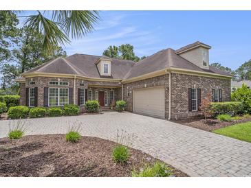 Brick home featuring a paver driveway, manicured landscaping, and a two-car garage at 280 Oatland Lake Rd., Pawleys Island, SC 29585