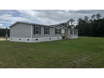 Well-maintained mobile home on a spacious lot featuring gray siding and black shutters at 71 Mohican Dr., Georgetown, SC 29440