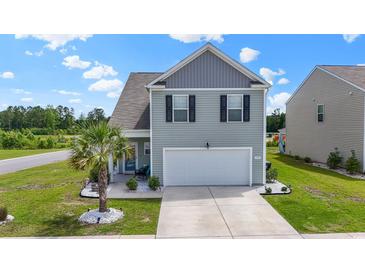 Charming two-story home featuring light gray siding, a two-car garage, and a neatly landscaped front yard with a small palm tree at 798 Woodland Farms Circle, Aynor, SC 29511