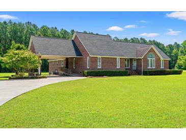 Charming brick home with manicured lawn, attached carport, and mature tree in a desirable neighborhood at 1752 Patriot Ct., Mullins, SC 29574