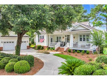 Charming single-Gathering home featuring a lush front yard and a welcoming front porch area with a detached garage at 179 Cottage Ct., Pawleys Island, SC 29585
