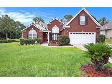 Charming red brick home with manicured lawn, shrubs, and a two-car garage, complete with a well-maintained landscape at 203 Old Hickory Dr., Conway, SC 29526