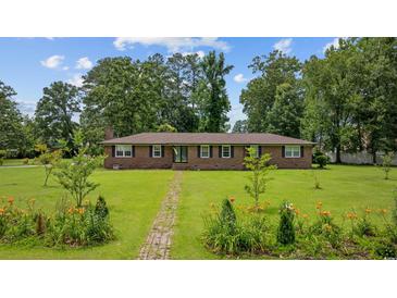 Charming brick home features a well-manicured lawn with landscaped flower beds and a brick walkway at 300 Crescent Dr., Conway, SC 29526