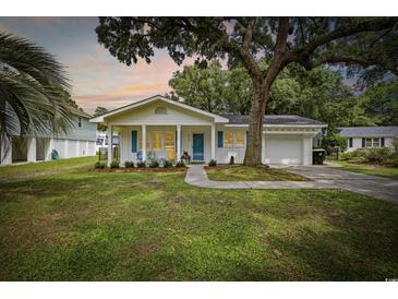 Charming single-story home featuring a well-manicured lawn and an inviting front porch with blue shutters at 412 Middleton Dr., Pawleys Island, SC 29585