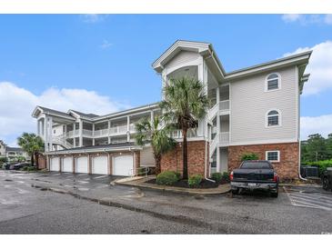 Exterior view of condo complex with attached garages and palm trees on a cloudy day at 4868 Dahlia Ct. # 202, Myrtle Beach, SC 29577