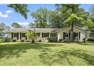 Charming single-story home with lush lawn, mature trees, and stylish black shutters at 520 13Th Ave. N, Surfside Beach, SC 29575