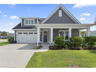 Charming home featuring a two-car garage, manicured lawn, and inviting front porch with decorative columns at 914 Mary Read Dr., North Myrtle Beach, SC 29582