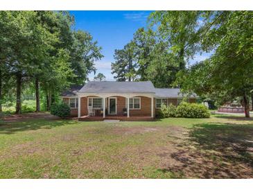Charming brick home featuring a cozy front porch and a well-maintained lawn, nestled among mature trees at 1217 S Highway 501, Marion, SC 29571