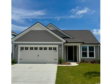 Charming single-story home features a two-car garage, gray siding, and a well-manicured lawn under a clear blue sky at 1514 Saw Palmetto St., North Myrtle Beach, SC 29582