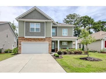 Charming two-story home with a two car garage, stone accents, manicured lawn, and a well-lit porch at 160 Juniata Loop, Little River, SC 29566