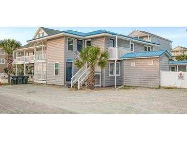 Charming two-story beach home featuring gray wood siding, a blue metal roof, and multiple elevated deck spaces at 202 27Th Ave. N, North Myrtle Beach, SC 29582