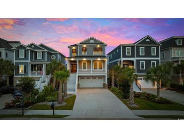 Charming two-story home featuring a two-car garage, well-manicured landscaping, and classic architectural details under a colorful sky at 496 West Palm Dr., Myrtle Beach, SC 29579