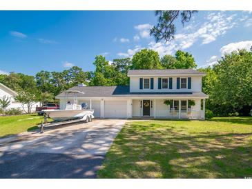 Charming two-story home with blue shutters, covered porch, two car garage, and a boat on the driveway at 66 Johnstone Ln., Georgetown, SC 29440