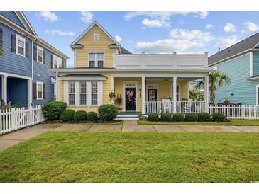 Charming two-story yellow home with a white picket fence and well-manicured landscaping at 721 Mckinley Way, Myrtle Beach, SC 29577