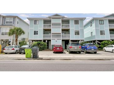 Three-story condo building featuring balconies, light blue siding, and parking underneath the building at 101 W First St. # A2, Ocean Isle Beach, NC 28469