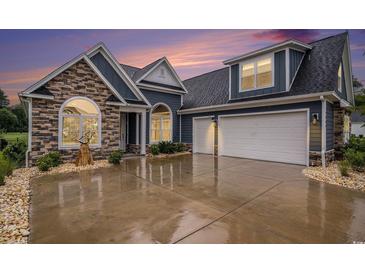 Beautiful blue home featuring a two-car garage, stone accents, and manicured landscaping at 1844 Wood Stork Dr., Conway, SC 29526