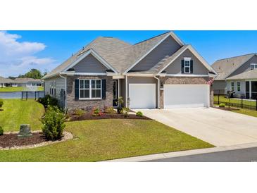 Charming home featuring a brick and siding facade, a two-car garage, and a beautifully landscaped front yard with lush greenery at 215 Kendrick St., Little River, SC 29566