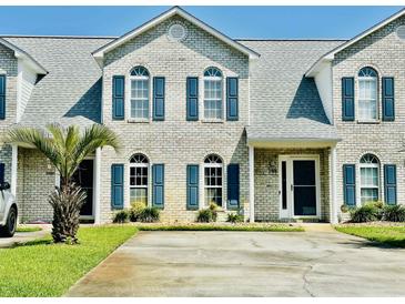 Charming brick townhouse featuring blue shutters, well-maintained landscaping, and a concrete driveway at 3978 Tybre Downs Circle # 3978, Little River, SC 29566