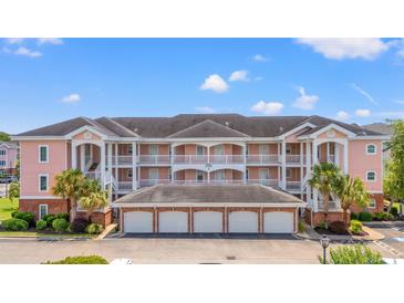 A beautiful multi-story pink condo building with white trim, balconies, and palm trees at 4846 Carnation Circle # 301, Myrtle Beach, SC 29577