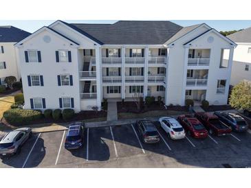Three-story condo building with white siding and blue shutters surrounded by mature landscaping and parking lot at 901 West Port Dr. # 712, North Myrtle Beach, SC 29582
