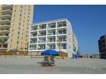 Beachfront condo building with multiple balconies and views, enhanced by beach chairs and a blue umbrella at 920 N Waccamaw Dr. # 2206, Garden City Beach, SC 29576