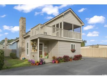 Charming exterior elevation featuring a second-story balcony, brick chimney, and colorful potted plants at 1710-C Edge Dr., North Myrtle Beach, SC 29582