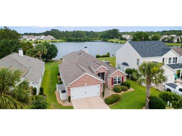Beautiful brick home with lush landscaping, an attached garage, and a tranquil lake view at 2210 Haystack Way, Myrtle Beach, SC 29579