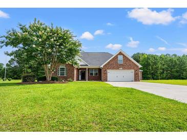 Charming brick home with a two-car garage, manicured lawn, and mature landscaping at 307 Russ Rd., Loris, SC 29569