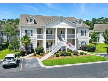 Inviting two-story condo building with white siding, well-maintained landscaping, and a prominent staircase entrance at 314 Black Oak Ln. # 102, Murrells Inlet, SC 29576